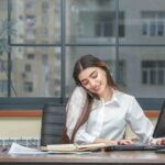 Young girl talking on the phone while working on the pc